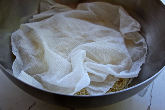Kadaif dough in a bowl covered with paper towel